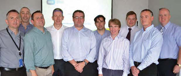 Ten men is shirts stand in line for a photo indoors.